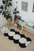 Irregular Ivory/Black Geometric Runner placed in a cozy reading nook with books and wall art.