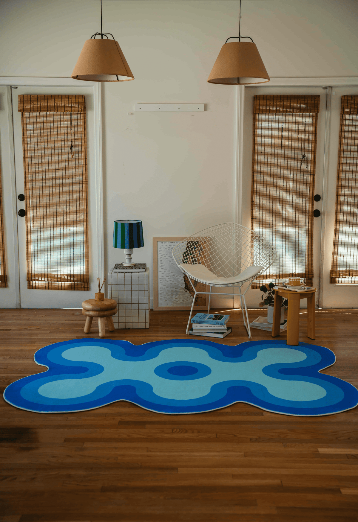 Full view of blue coral-shaped rug centered in a living room with double doors, pendant lamps, and minimalist decor.