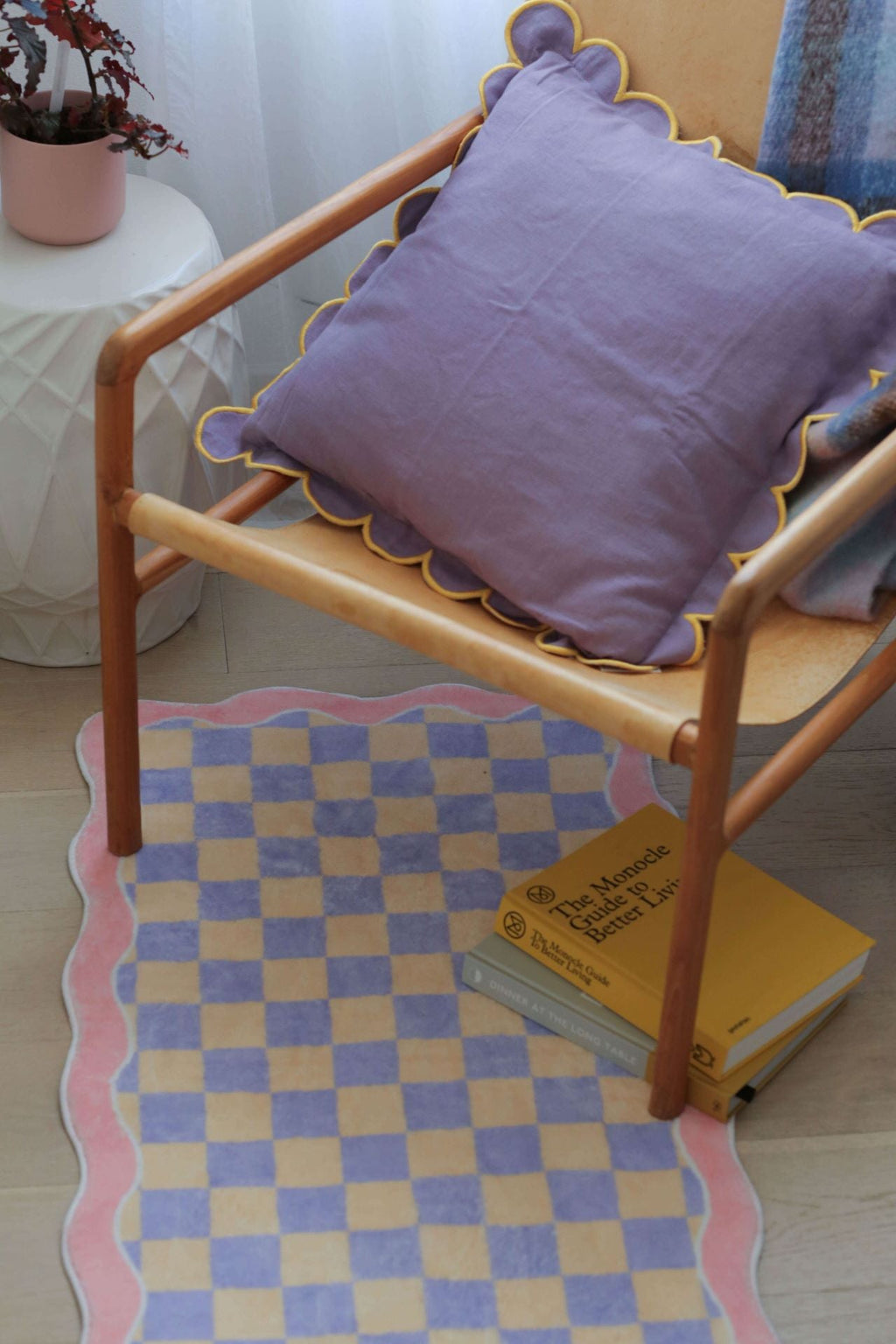 A close-up view of the Mellow Pastel Runner partially under a chair, styled with a scalloped pillow and layered throws.