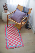 Pink and Blue Lace Checkerboard Runner under a wooden lounge chair with a scalloped lilac pillow and soft throw.