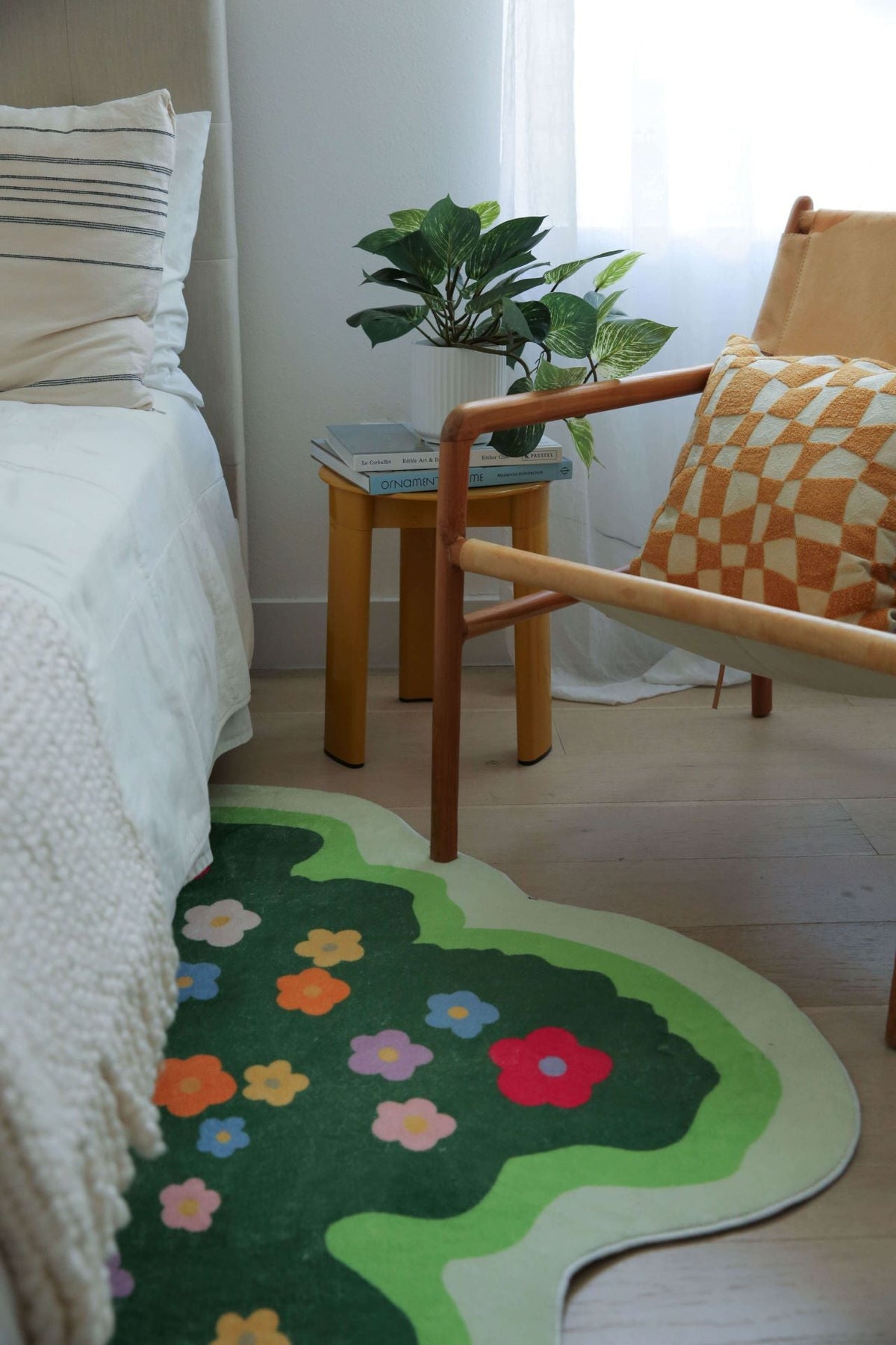 Close-up view of the floral irregular rug next to a mustard checkered pillow and side table.