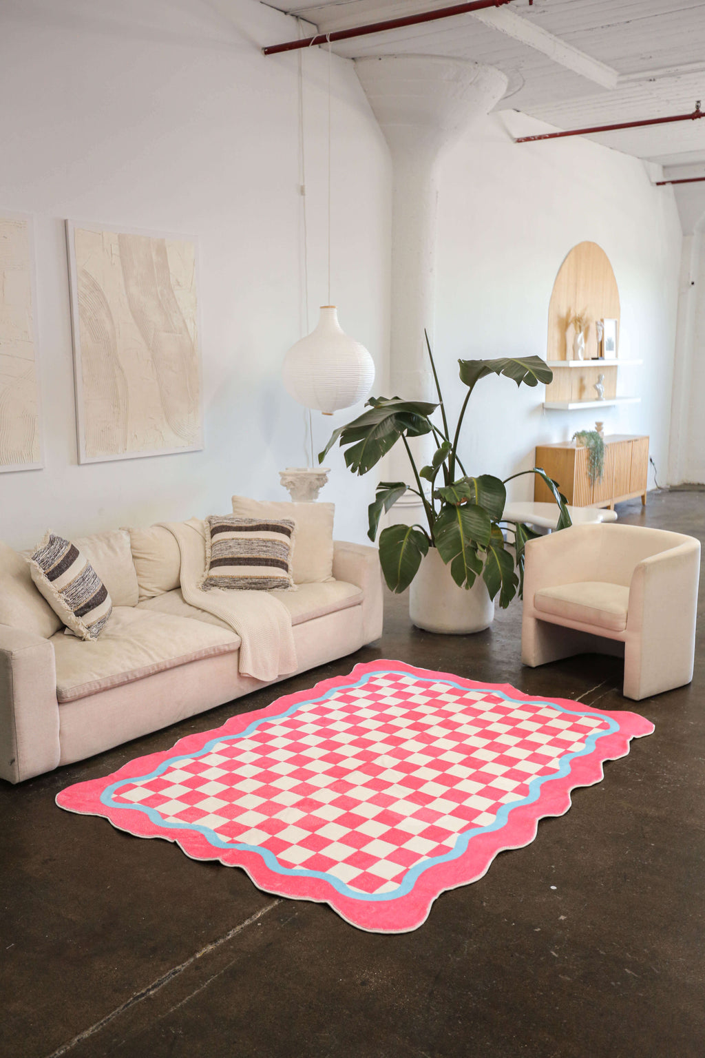 The checkered rug placed in a bright, open space with minimalistic furniture and high ceilings.