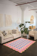 Pink and purple floral rug in a spacious loft setting, complementing a neutral-toned sofa and large potted plant.