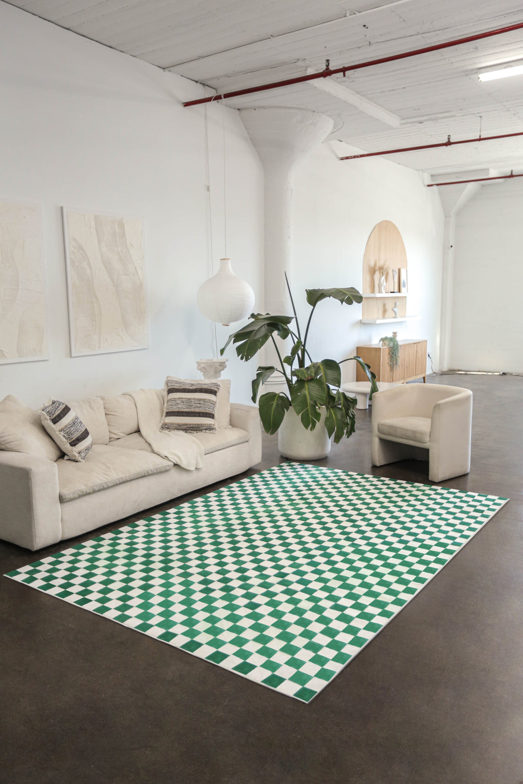 Green and white checkered rug in a minimalist loft setting with neutral-toned furniture and polished concrete floors.
