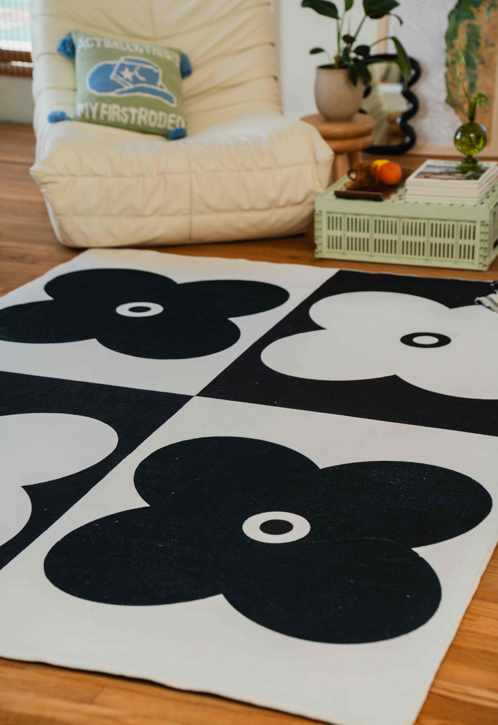 Black and white flower rug in a cozy corner with lounge chair and mint green crate-style coffee table.