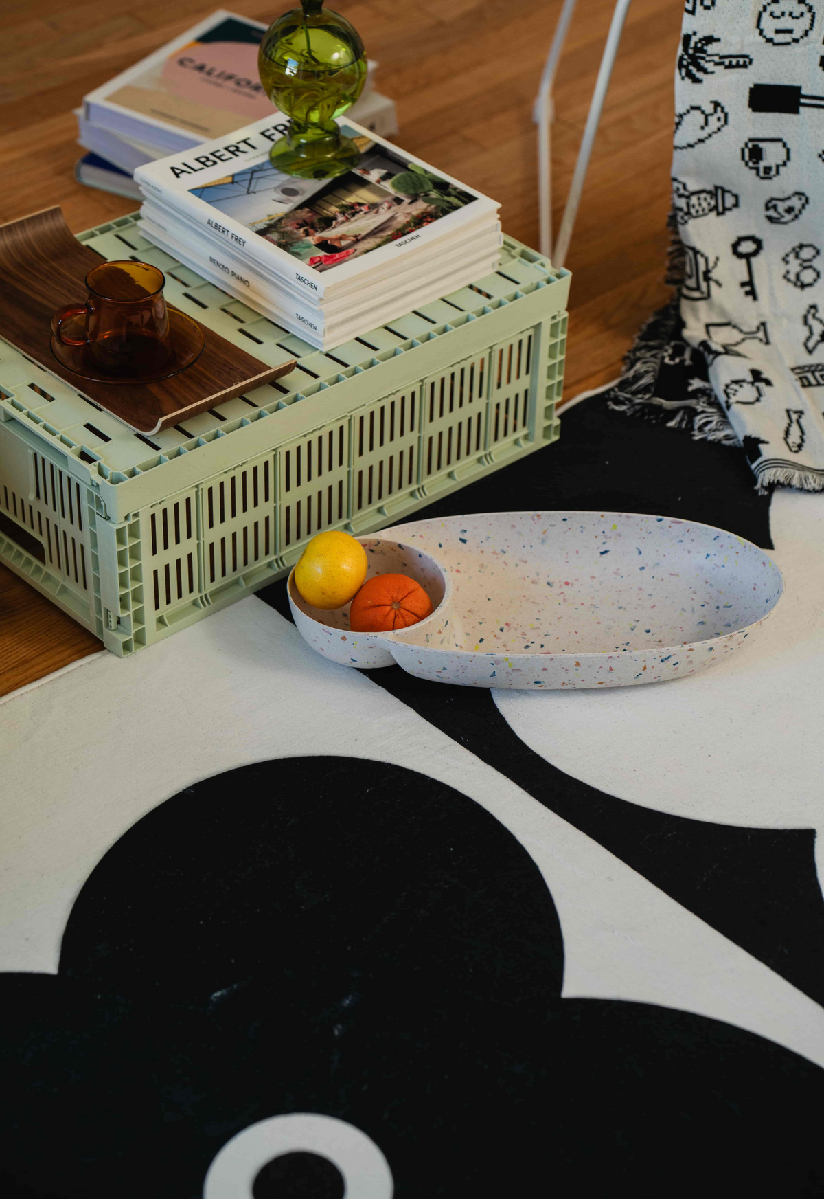 Black and white floral rug with books and fruit bowl on crate-style coffee table.