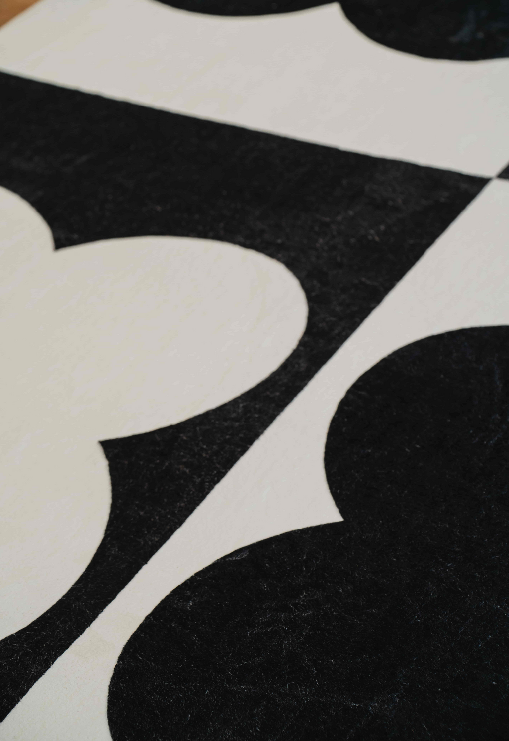 Angled detail view of the rug’s bold black and white floral print pattern on hardwood floor.