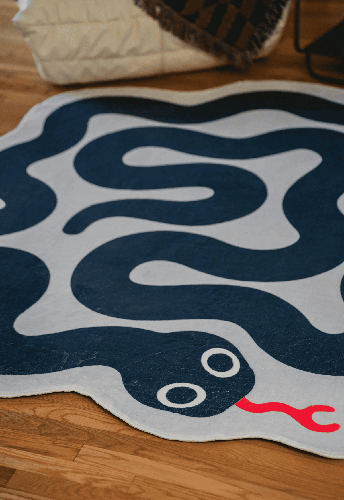 Navy and white snake rug next to a cream lounge chair and tasseled throw blanket.