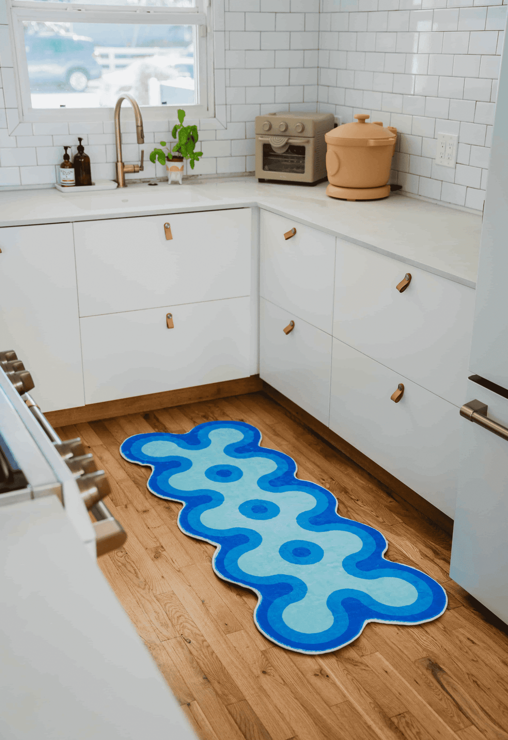 Irregular coral design runner in shades of blue placed in a white cabinet kitchen.