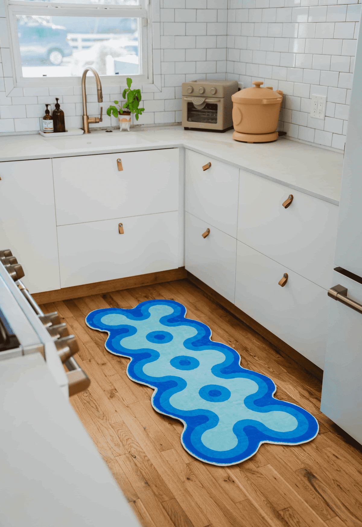 Irregular coral design runner in shades of blue placed in a white cabinet kitchen.