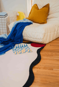 Close-up view of the ivory rug under a lounge chair, paired with a blue throw and a chess set.