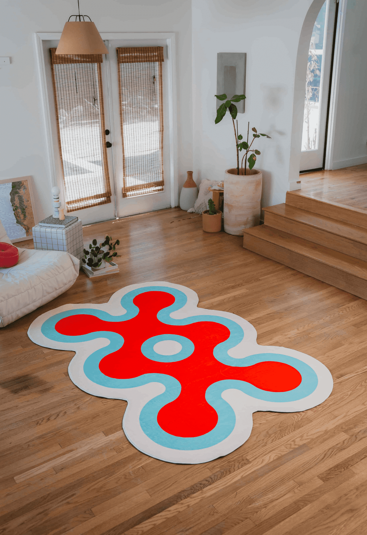 Irregular Coral Design Rug by Johann Banta in red, white, and blue on wooden floor, styled in a bright modern living room.