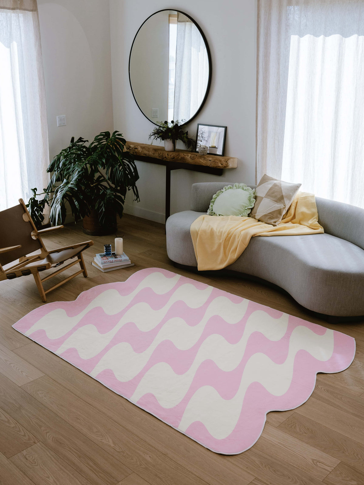 Full view of pastel pink and yellow wavy rug under curved sofa with yellow throw in bright living room.