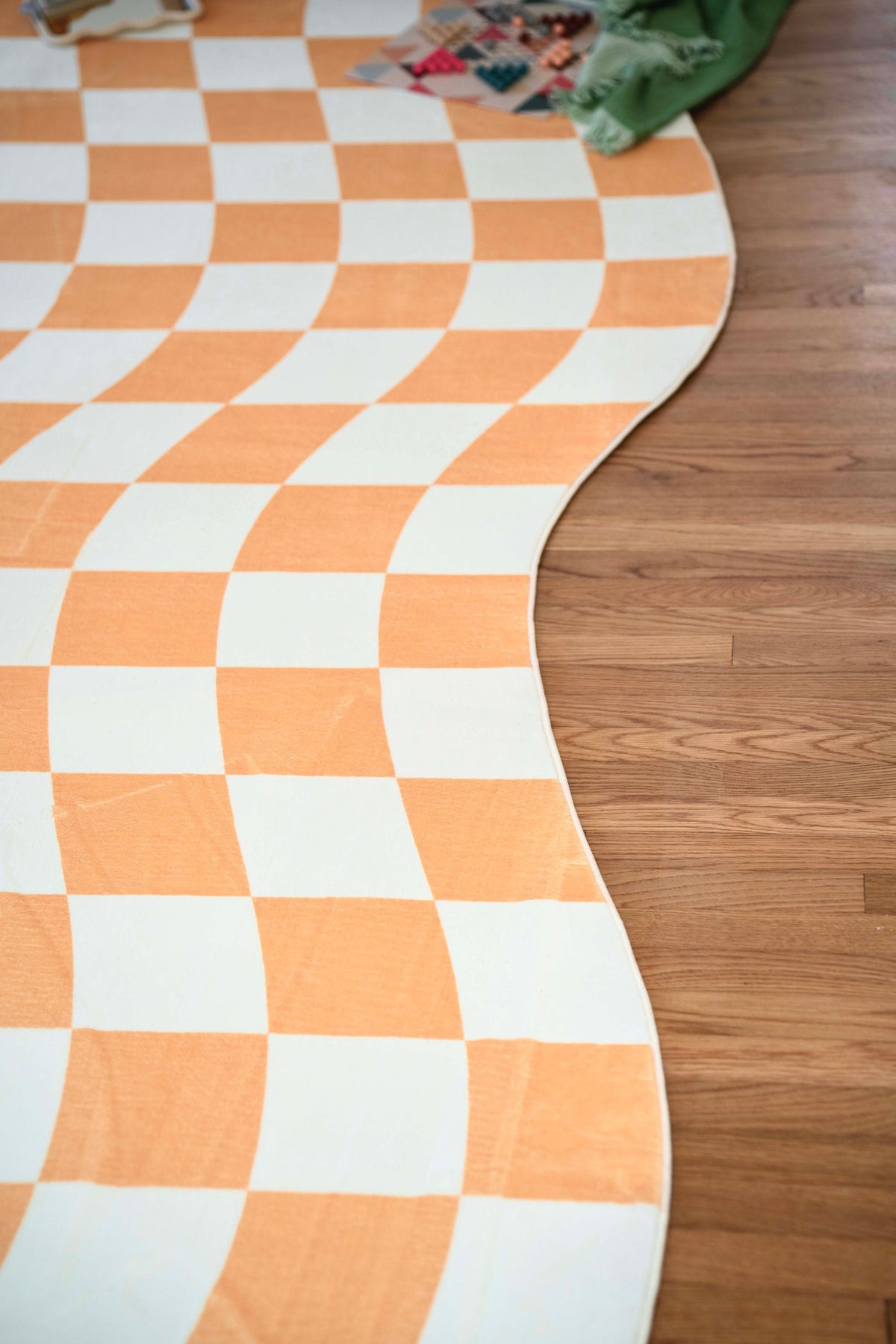 Close-up of the Yellow Wavy Checkered Rug’s curvy edge, highlighting the flowing check pattern on wood floor.