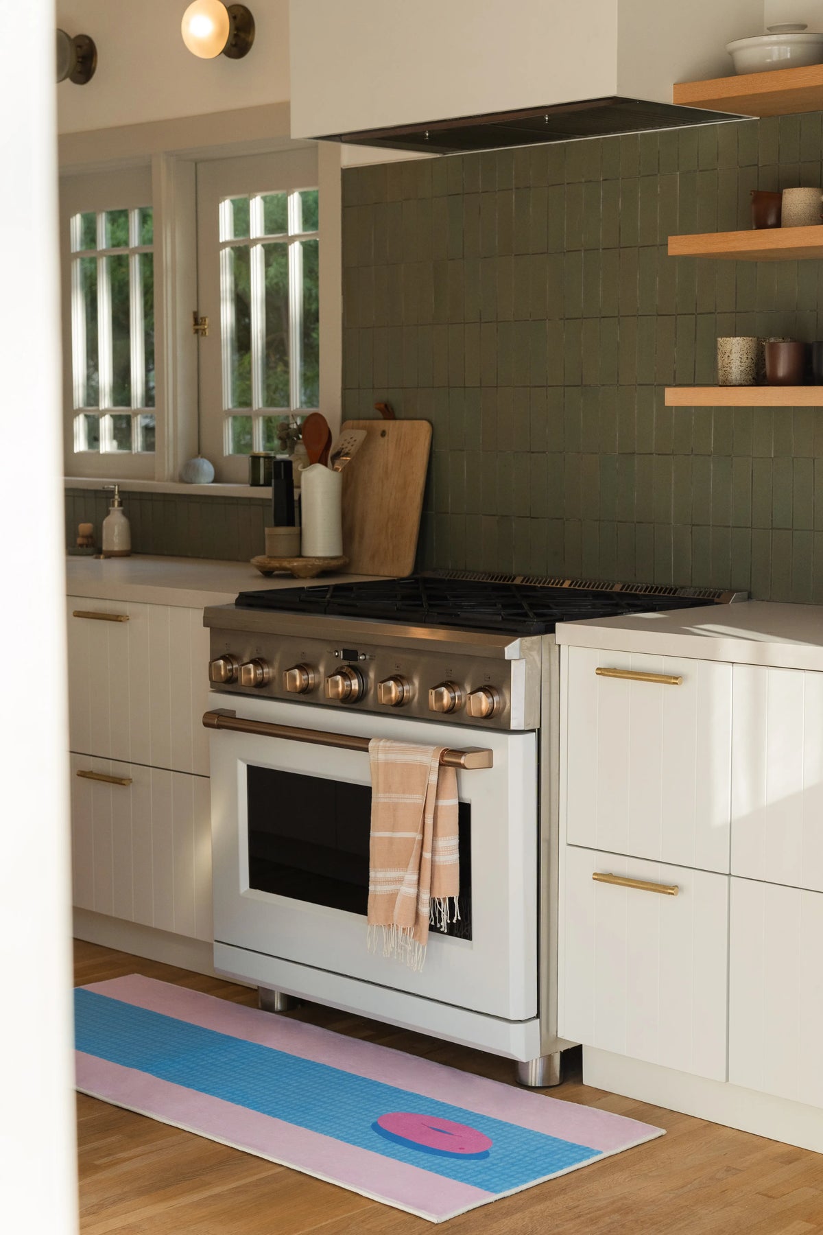 Funky pool runner rug in front of a white kitchen range, showing a blue tiled center and pale pink border