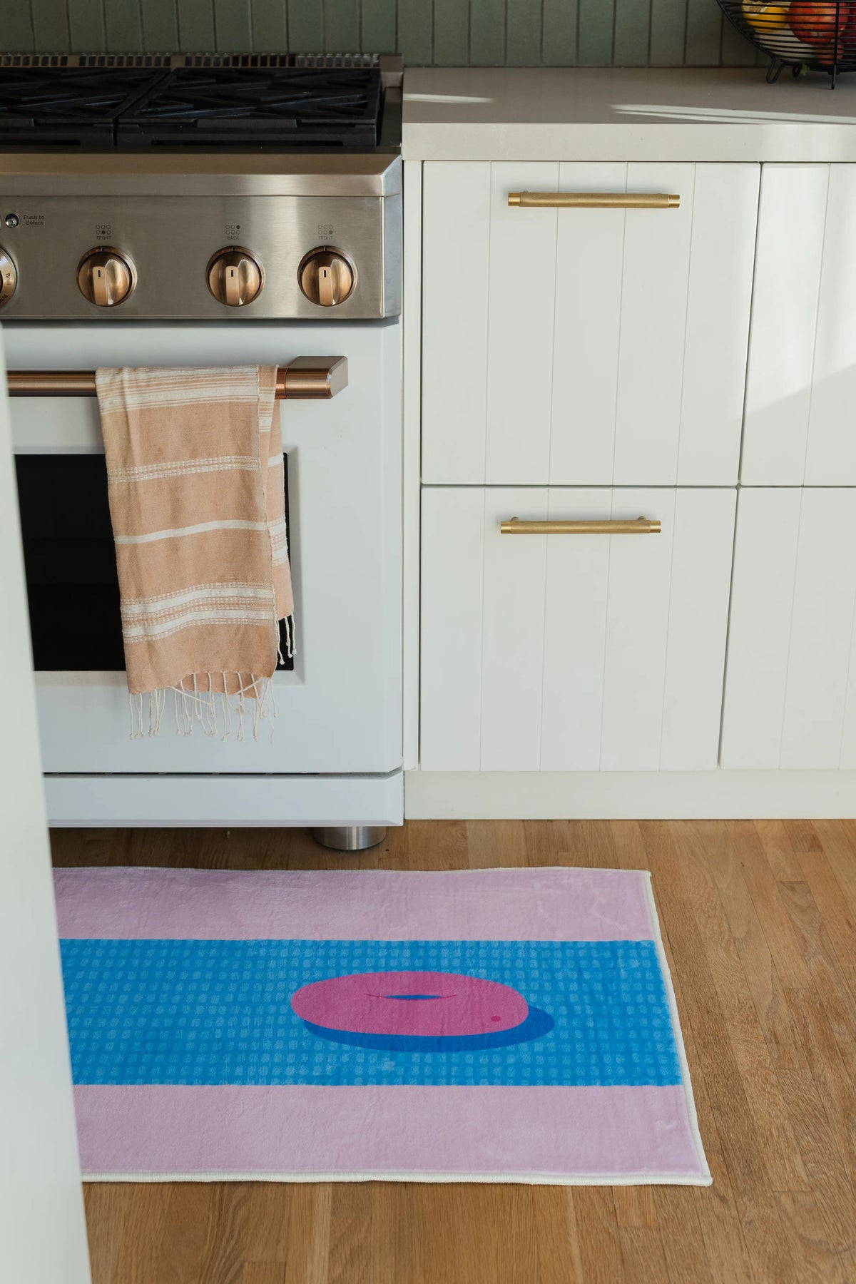 Modern pool inspired runner beside white lower cabinets, with a blue striped center and pink border on the floor