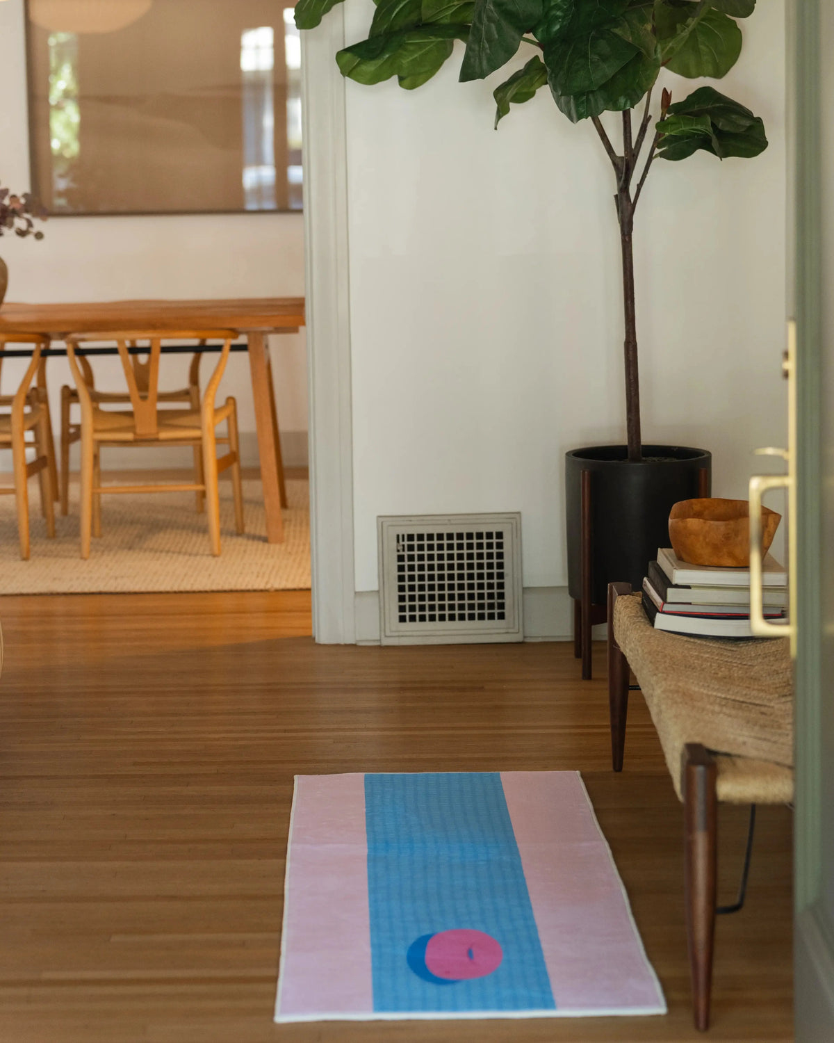 Long blue and pink runner rug in a bright hallway corner, with a pool float graphic on a light wood floor