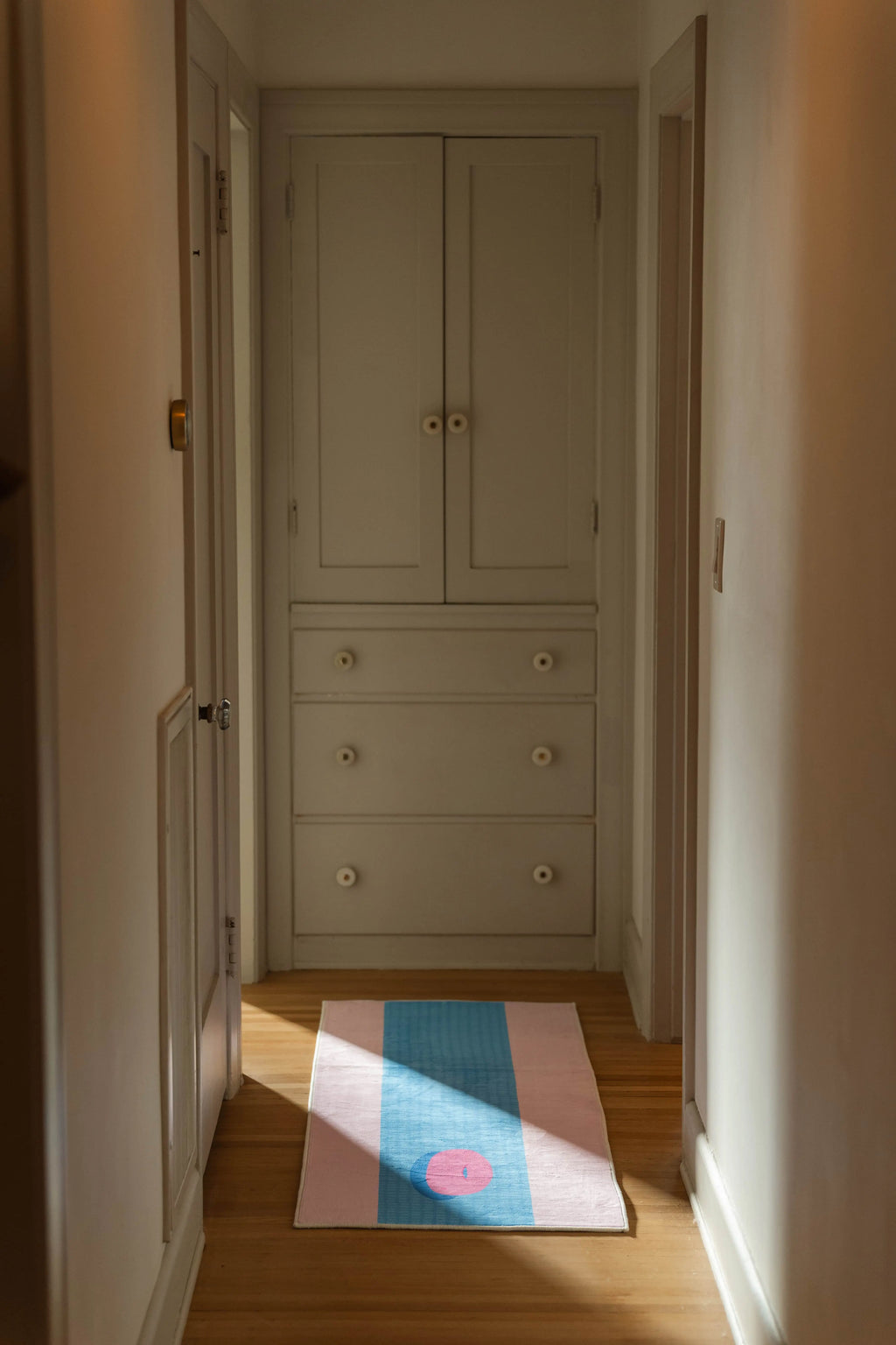 Blue and pink graphic runner rug laid along a hallway, with a circular float motif near the far end