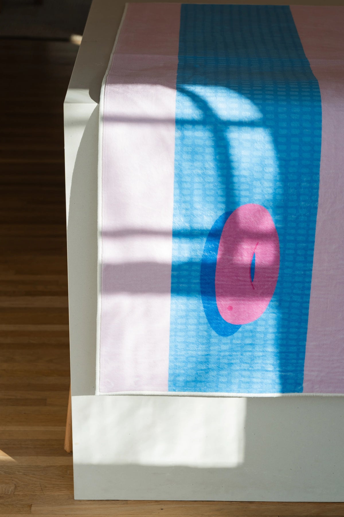 Close up of the funky pool runner rug with sunlight across the surface, highlighting the pink float on the blue field