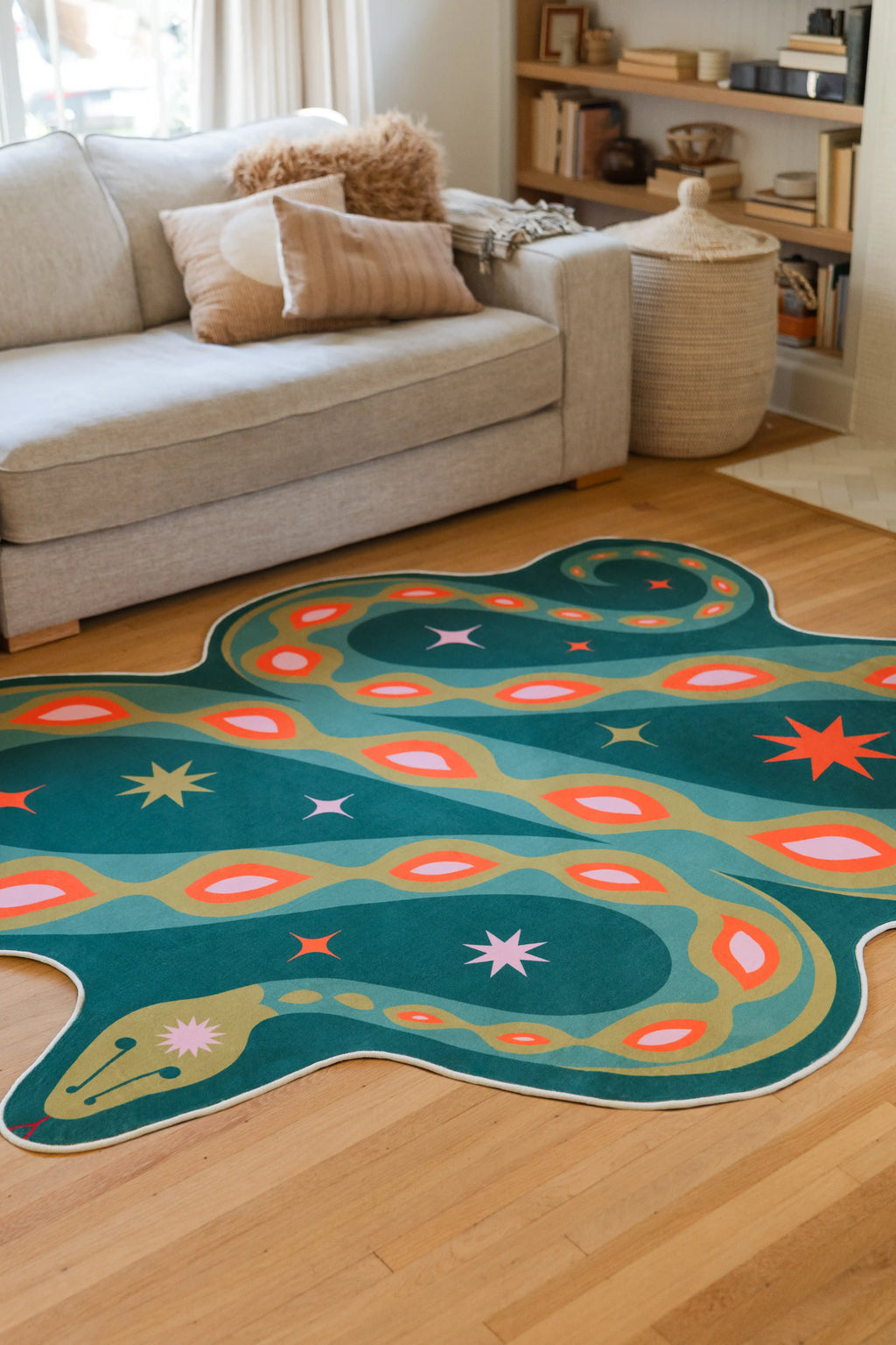 Partial view of the green irregular shaped rug beside a beige sofa, with curved body lines and orange spots