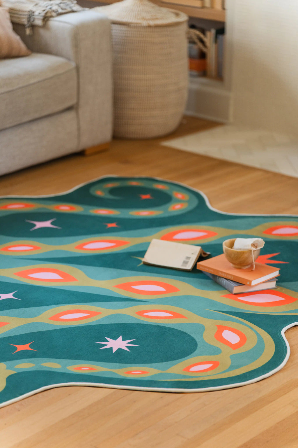 Green snake rug stretched across the floor near a beige sofa and books, with layered curves and graphic markings