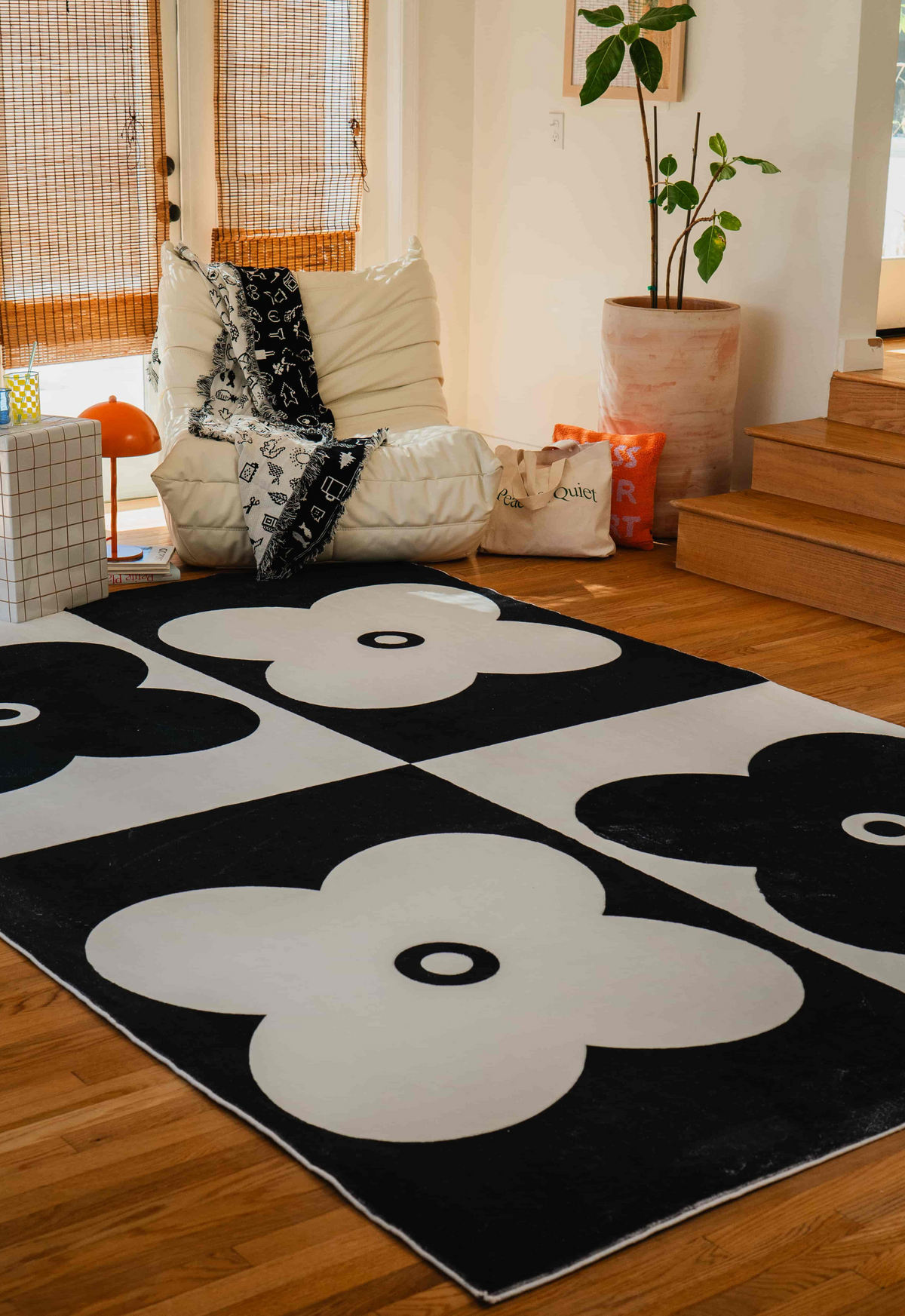 Black and white clover rug in a cozy corner with a lounge chair, throw, and soft morning light filtering in.