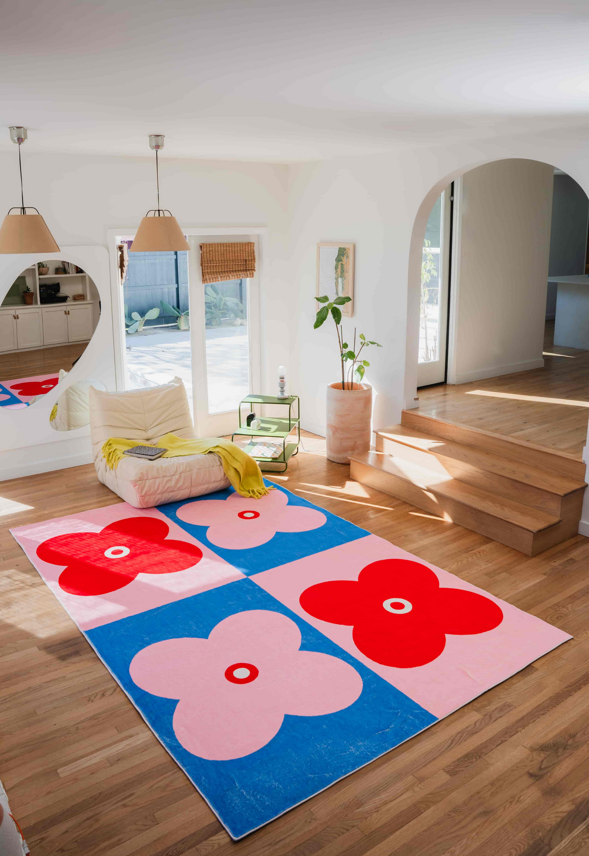 Pink and red variation of the four leaf clover rug brightening up a cozy corner with natural light and soft seating.