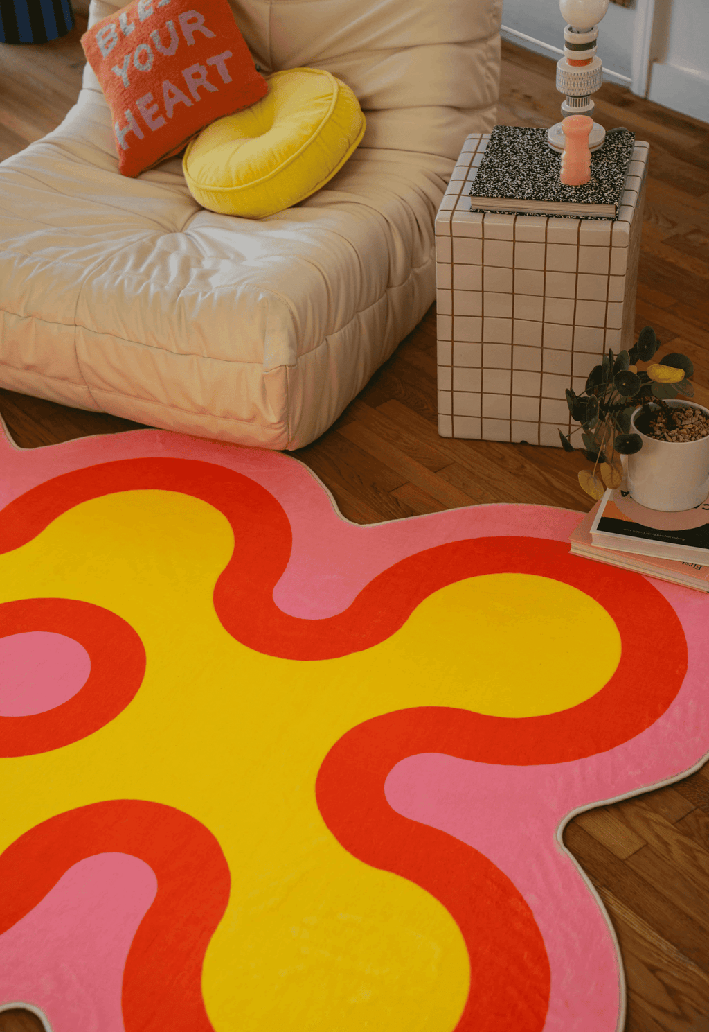Close-up of yellow and red coral-shaped rug with pink outline next to a white lounge chair and tiled side table.