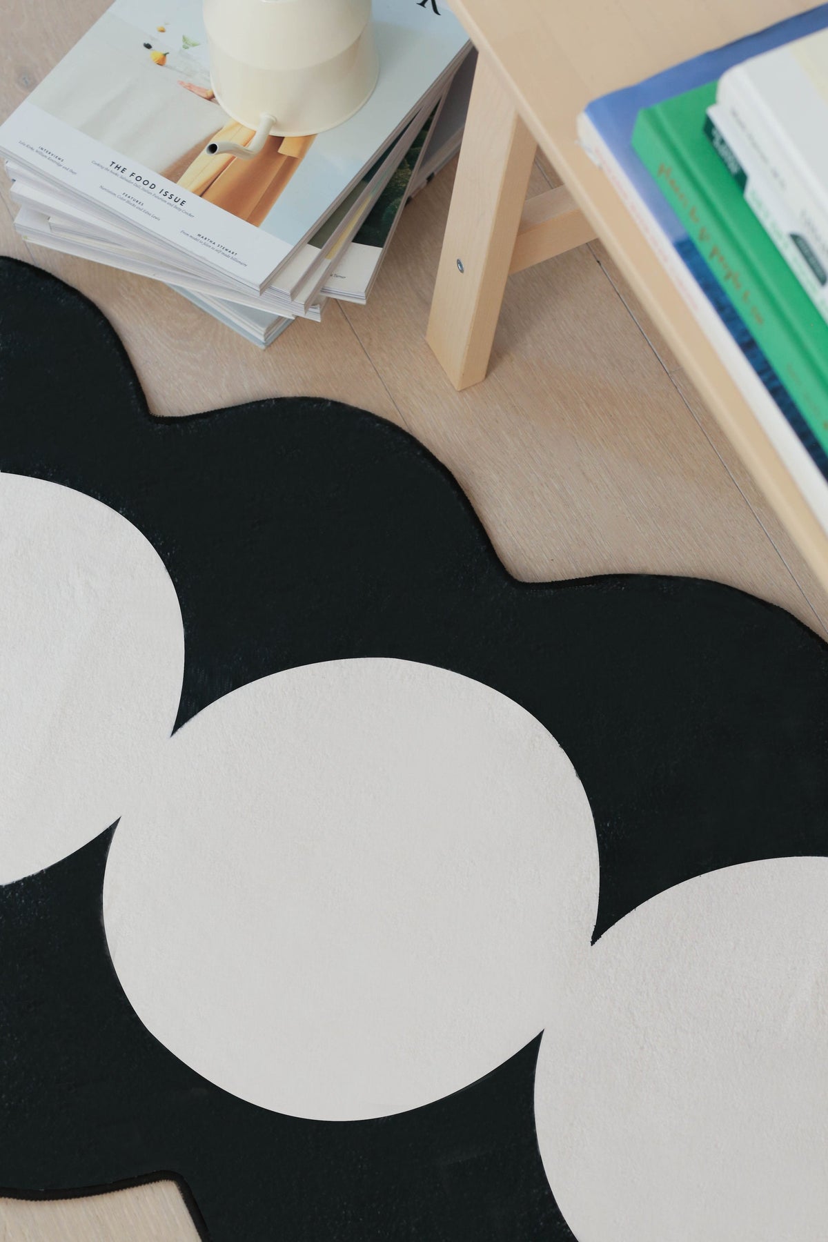 Close-up of the runner's bold black scalloped edge and ivory circular pattern beside a wooden bench.