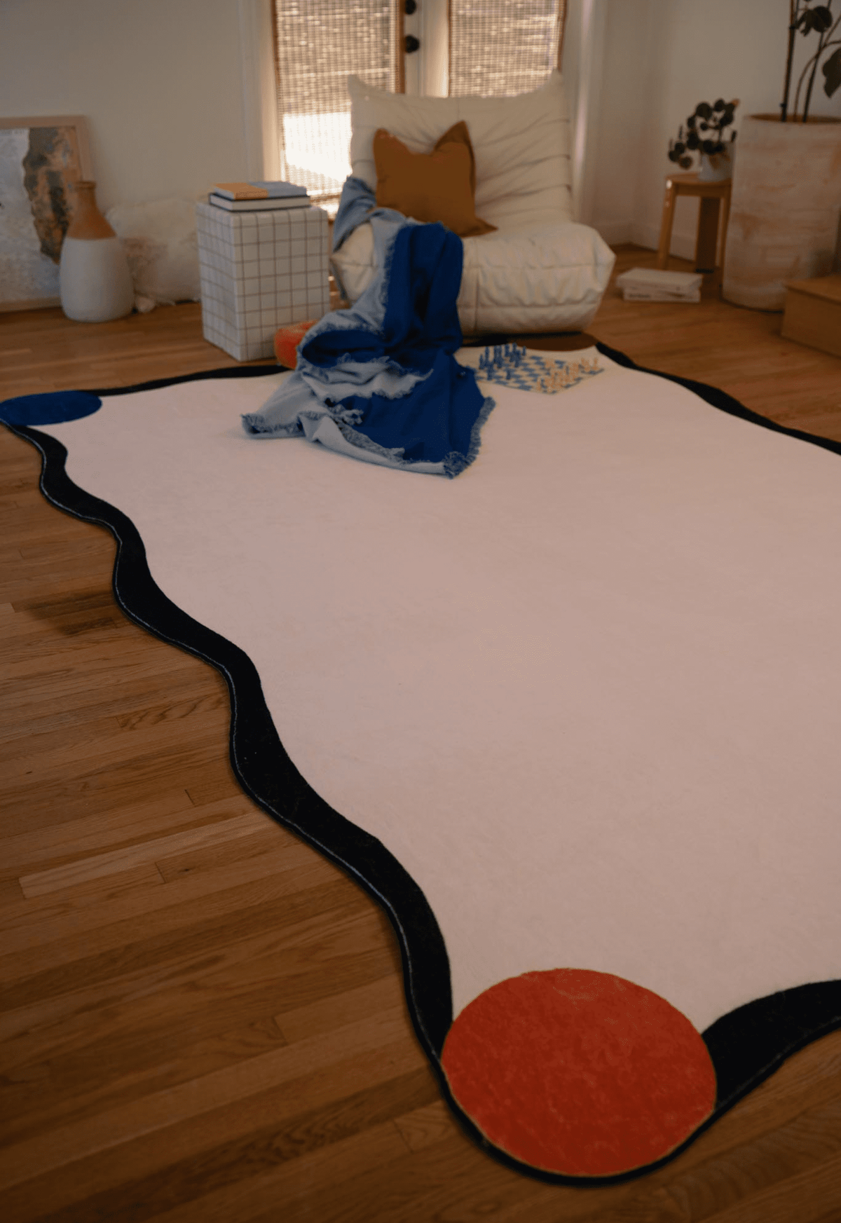 A wider view of the same ivory rug, showing its colorful circular accents and organic silhouette, laid out in a warm-toned interior space.