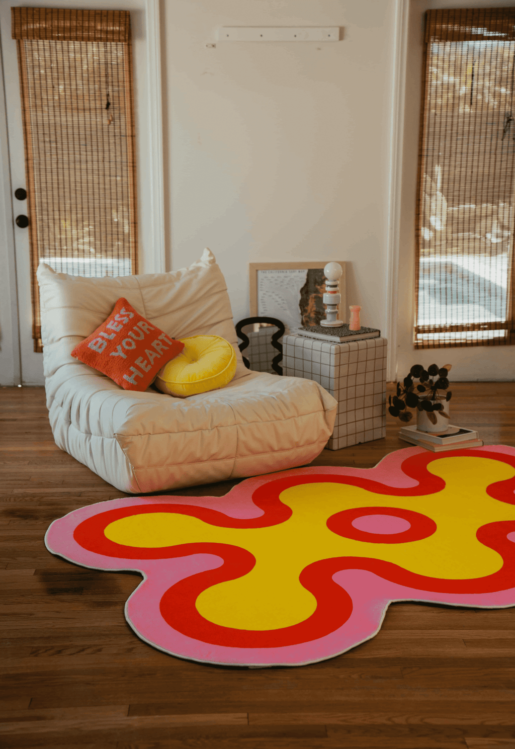 Yellow coral rug with orange and pink details in front of lounge chair in sunlit room.