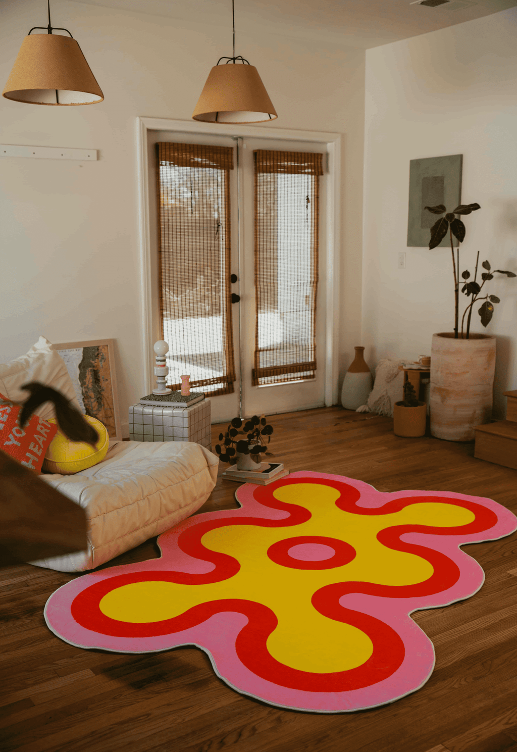 Yellow and red coral-patterned rug in front of a white lounge chair and low table in a sunlit living space.