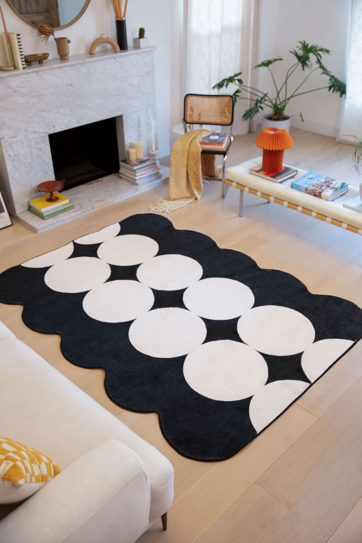 Irregular Ivory/Black Geometric Area Rug placed in a modern living room with a marble fireplace and cozy neutral-toned furniture.
