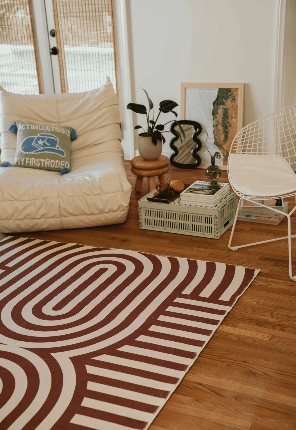 Close-up of the rug partially under a vintage floral sofa in a cozy room with a gallery wall of retro framed prints and neon bar signs.