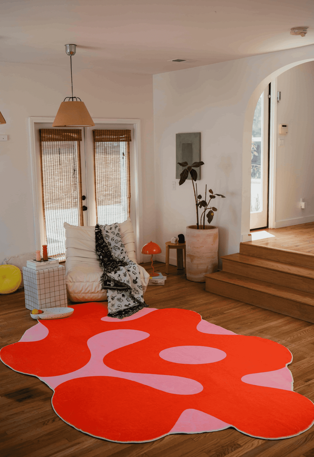 Irregular Orange Moss Design Rug by Johann Banta placed at the center of a bright room with wood floor and arched entry.