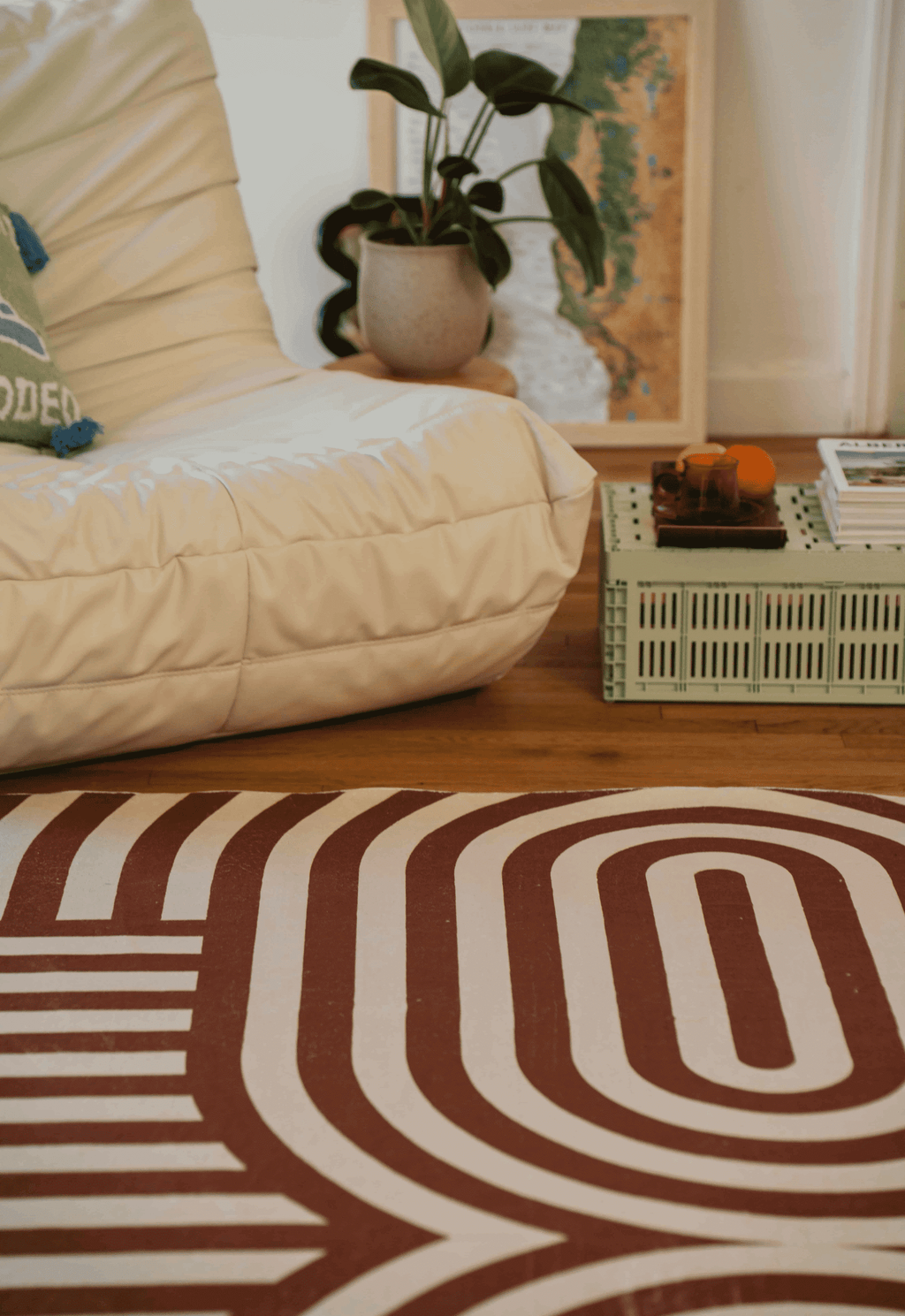 A white armchair and mint crate table sit atop the curvy brown stripes rug, styled with citrus and glassware for a cozy corner.