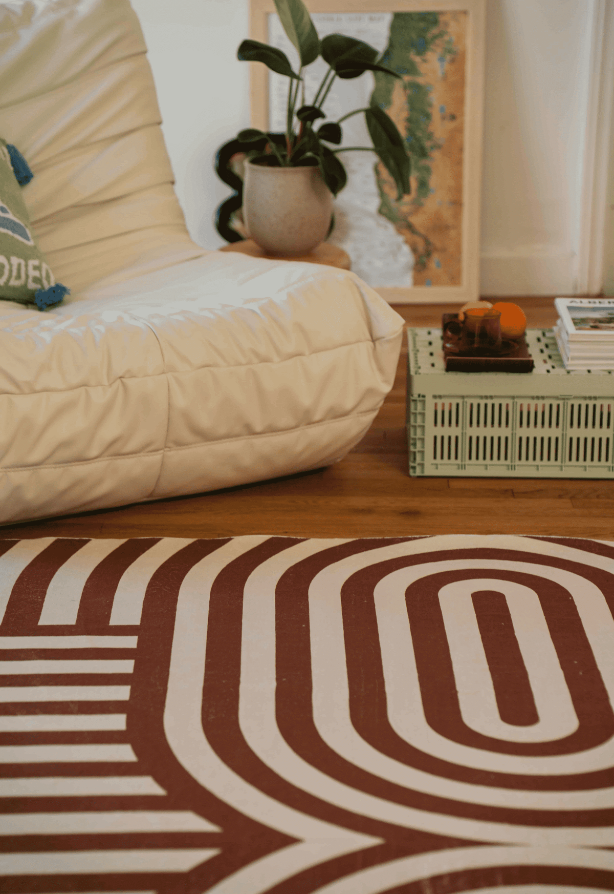 A white armchair and mint crate table sit atop the curvy brown stripes rug, styled with citrus and glassware for a cozy corner.