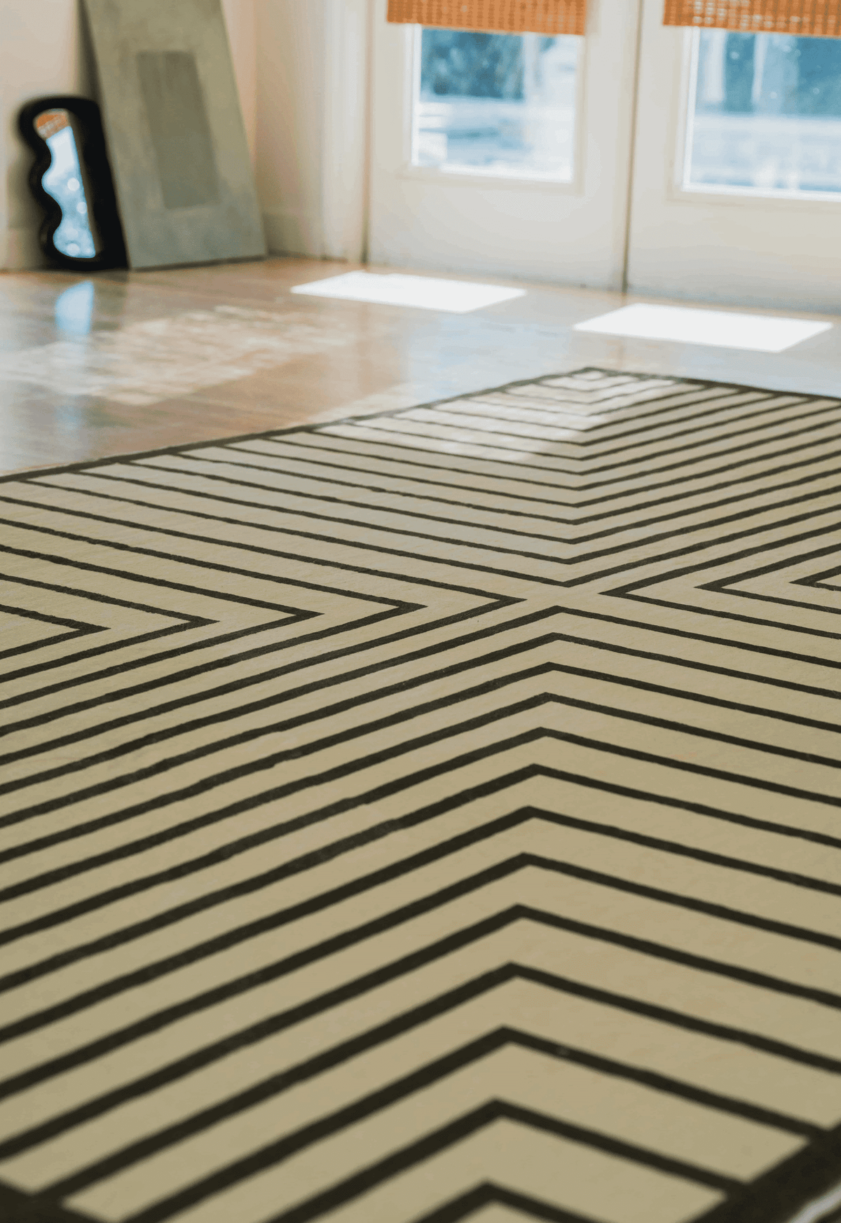 Wide view of Olive Green Striped Minimalist Rug in bright living room with wood floors, steps, and white archway.