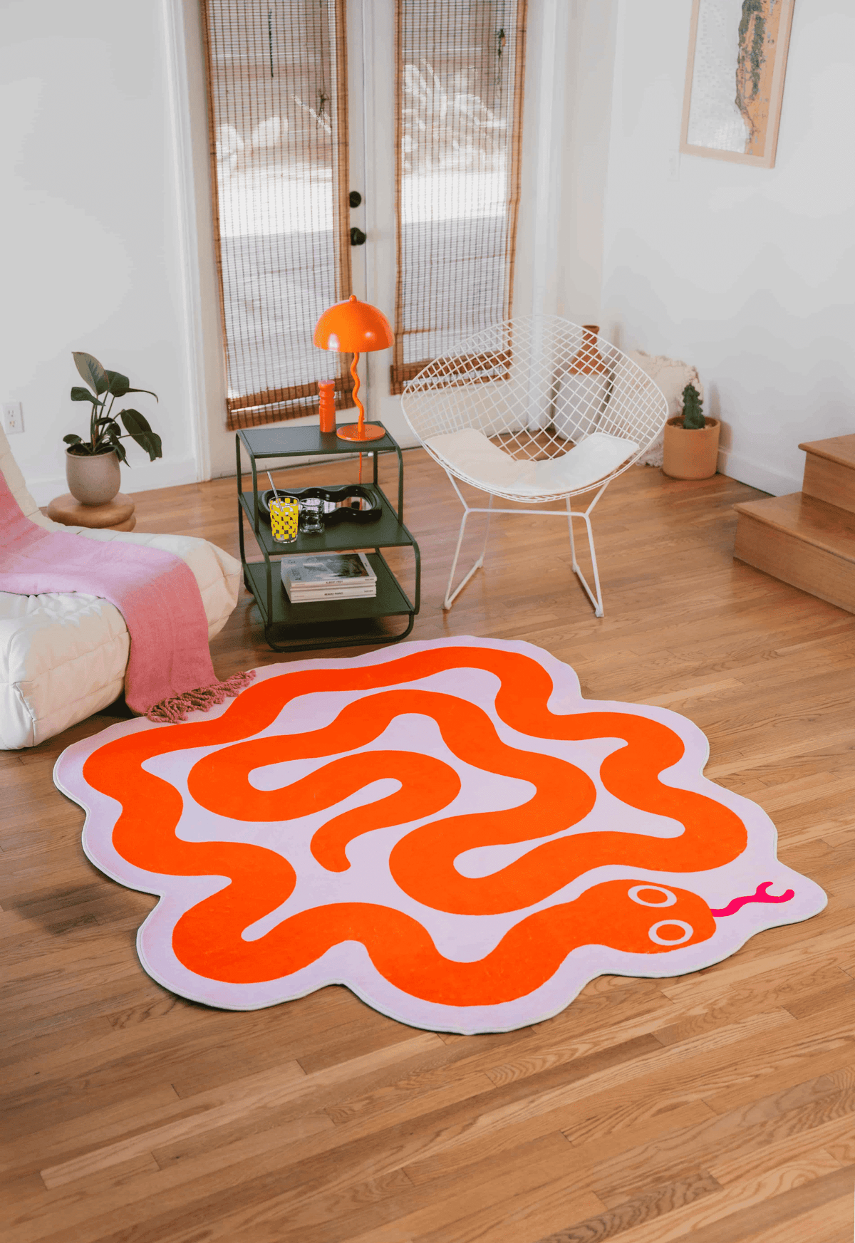 Bright orange snake-shaped rug in pink outlines, adding whimsy and boldness to a modern living room setup.