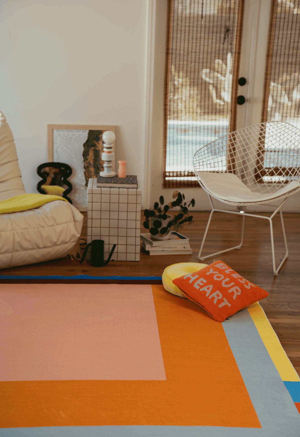 Living room scene with a white armchair, grid side table, and Modern Geometric Print Rug in orange, pink, blue, and yellow.