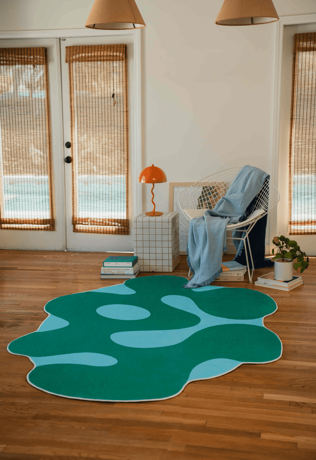 rregular Green Moss Design Rug by Johann Banta in a cozy reading nook with white chair, books and warm wooden floor.
