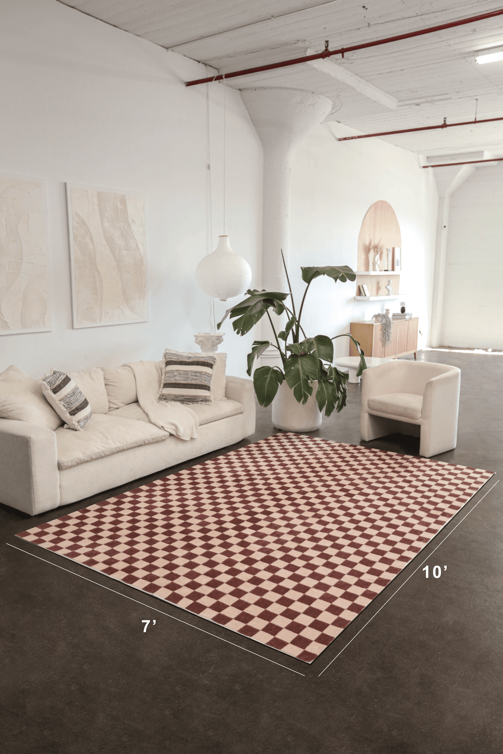 A wide studio shot shows the checkered rug’s full 7' x 10' size beneath a cream sofa, softening the industrial floor.