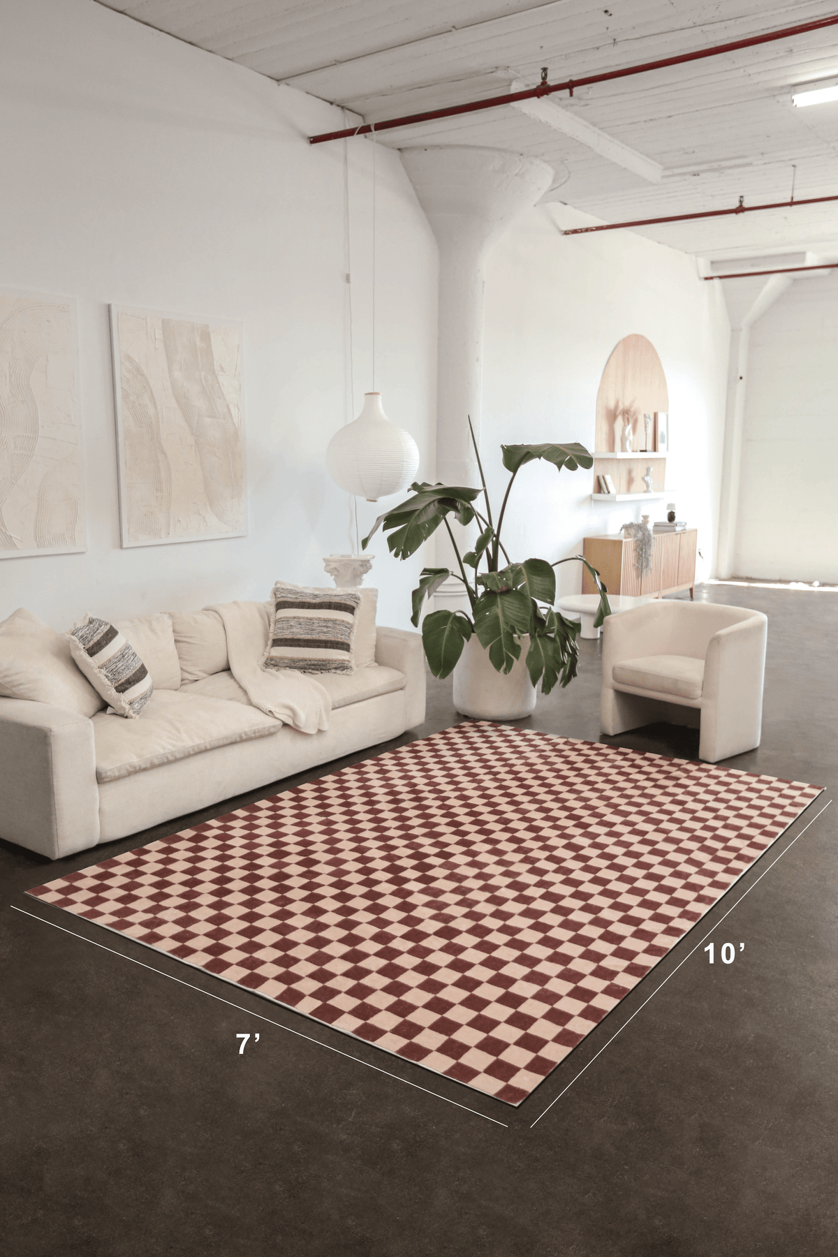 A wide studio shot shows the checkered rug’s full 7' x 10' size beneath a cream sofa, softening the industrial floor.