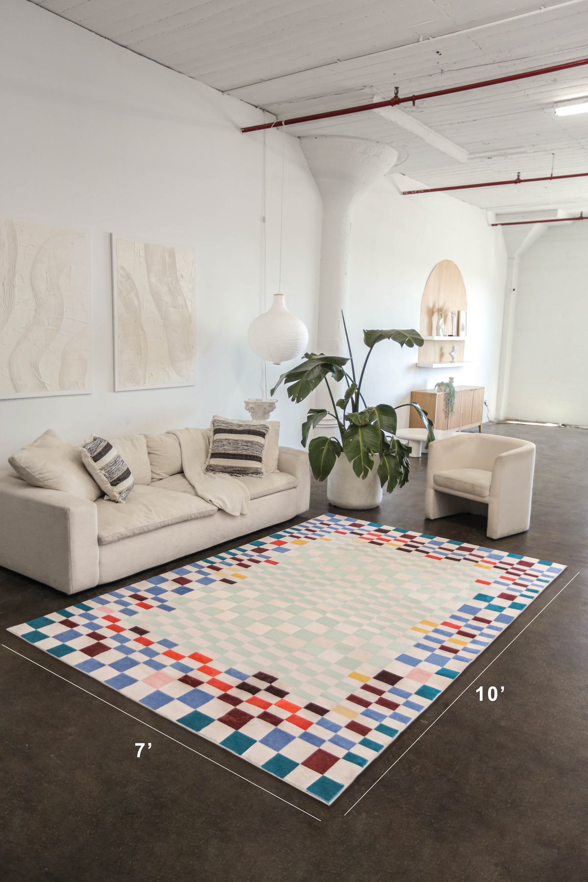 Pixel checkered rug in a spacious loft, styled with a neutral sofa and accent chair, measuring 7 by 10 feet.