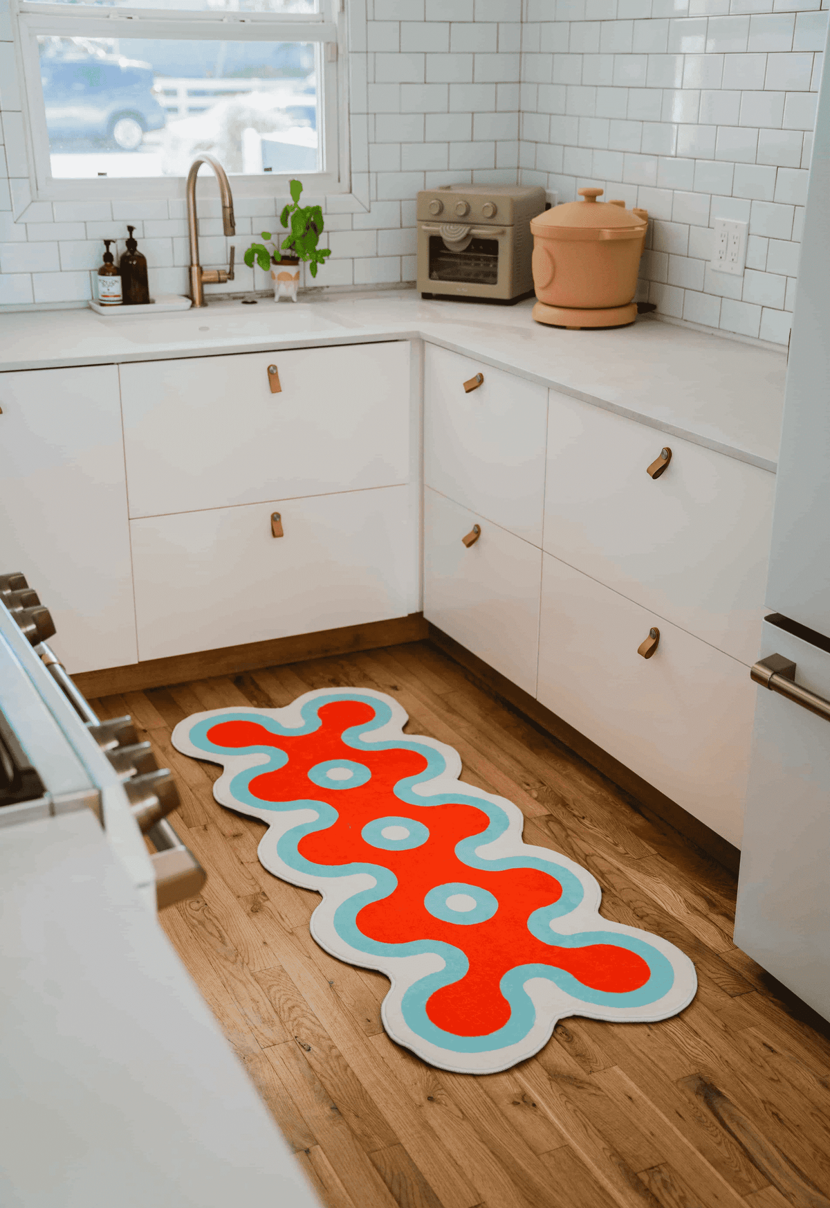 Coral design runner in red and aqua hues placed on kitchen floor, surrounded by white cabinetry and minimal kitchen setup.