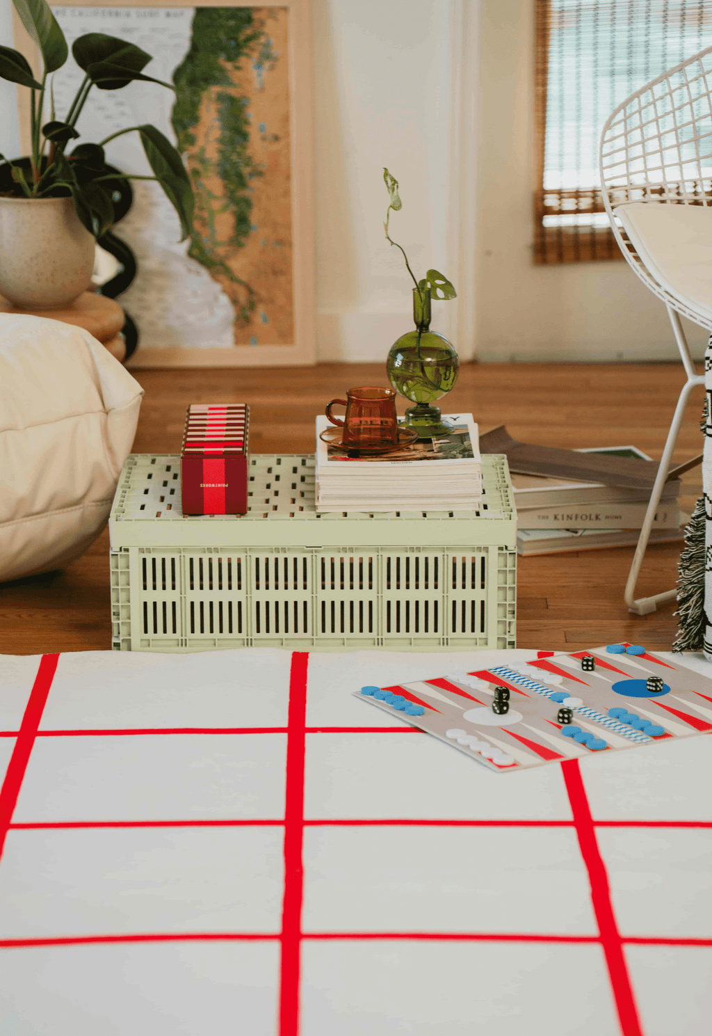 Red and white grid rug in living room, paired with mint crate coffee table, books, and green vase holding a vine.