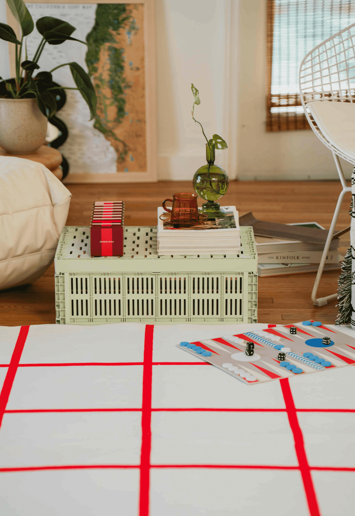 Red and white grid rug in living room, paired with mint crate coffee table, books, and green vase holding a vine.