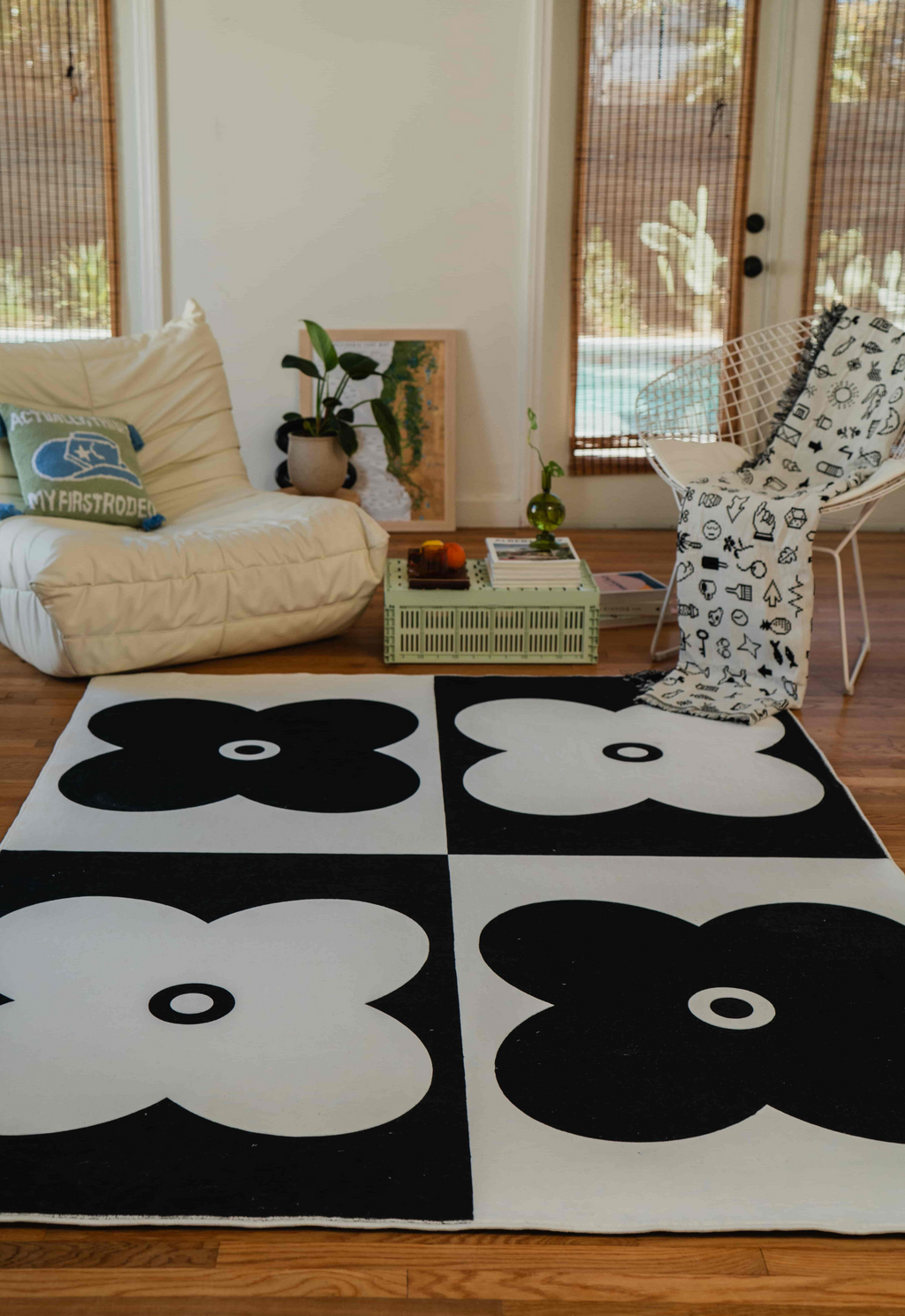 Minimalist flower rug in black and white tones, paired with cozy seating and a patterned throw.