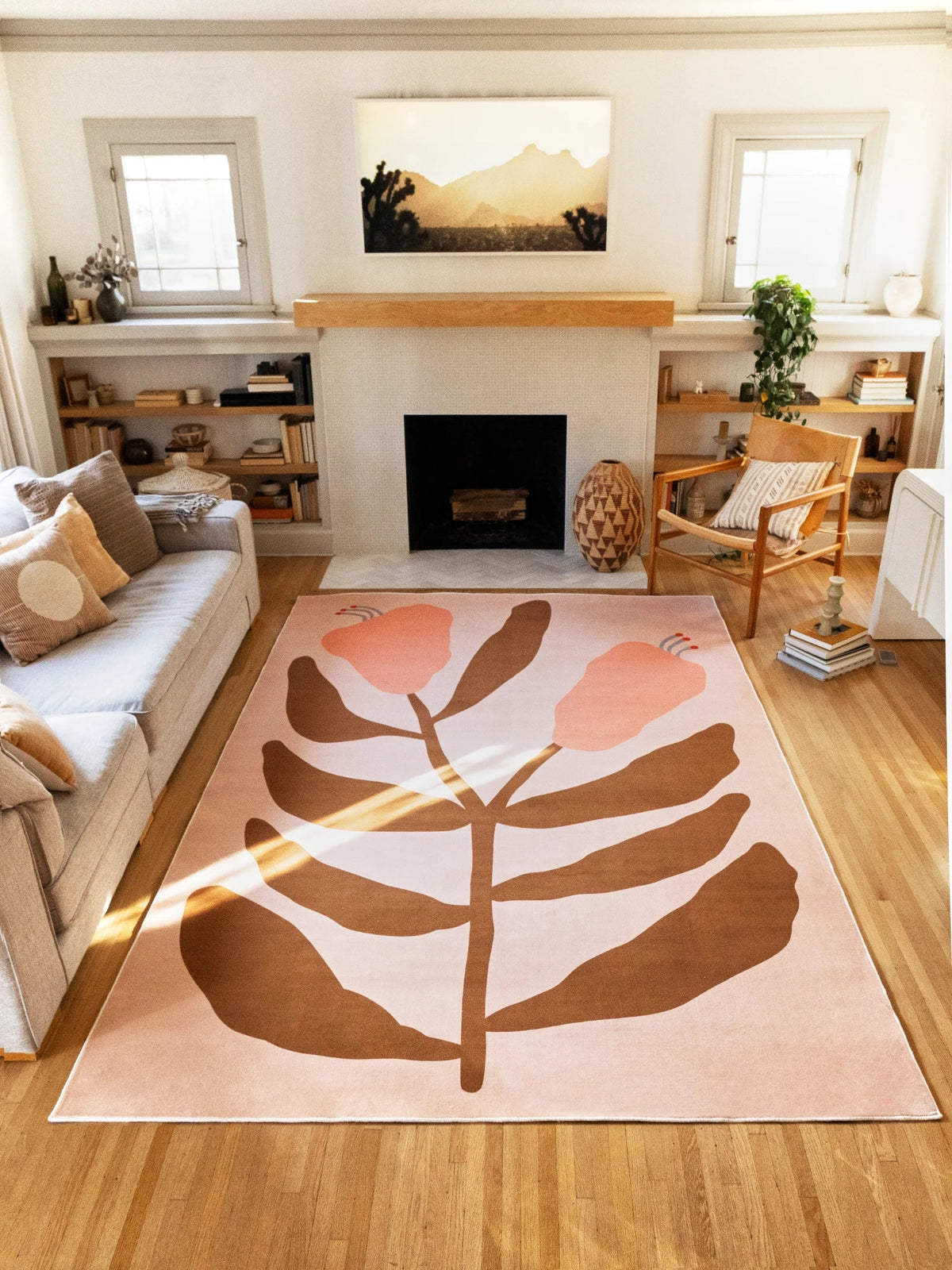 Wide room view of the beige flower rug between a sofa and fireplace, showing brown leaf forms and peach buds