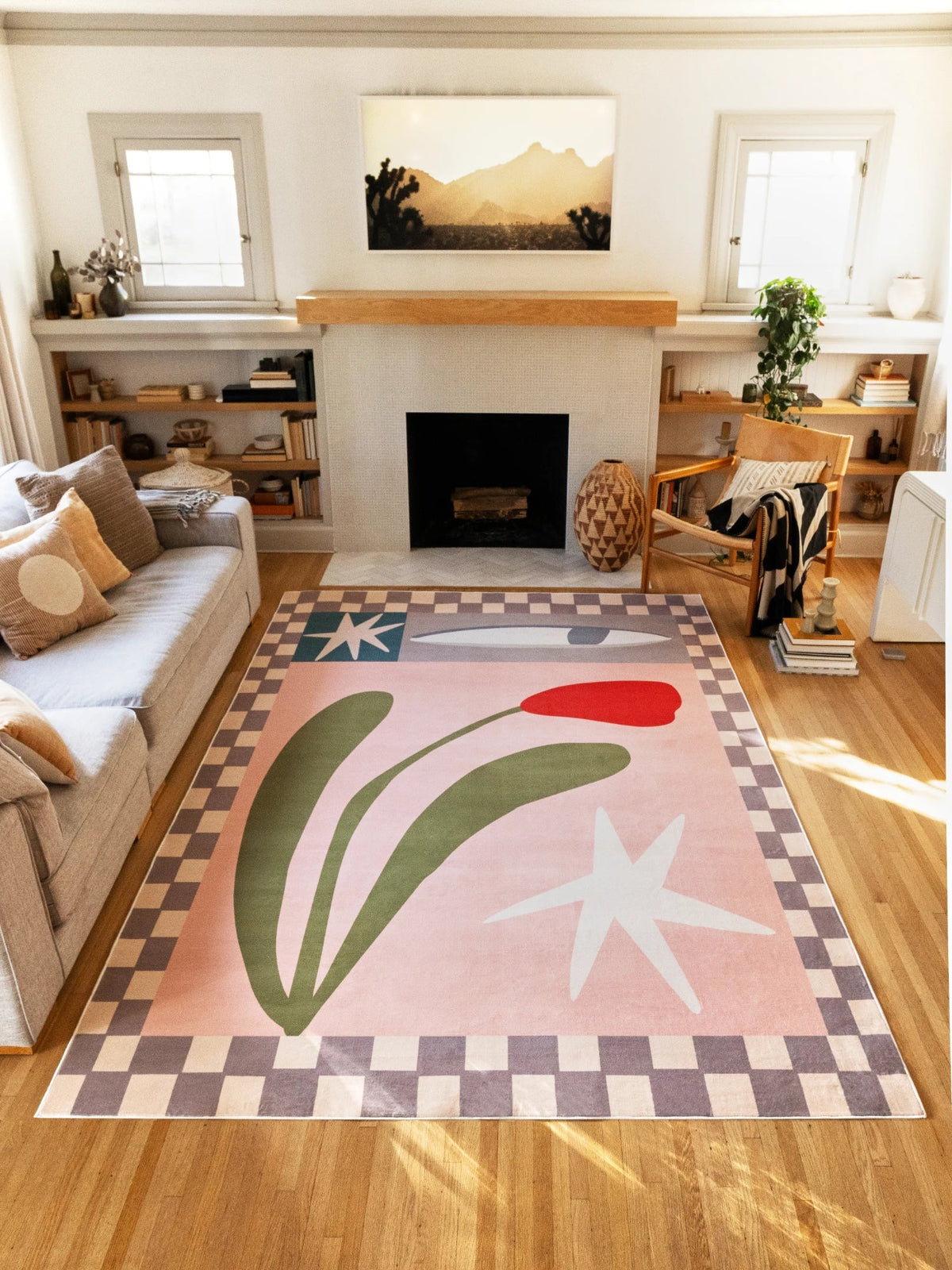 Checkered floral rug between a sofa and fireplace, showing blush pink ground and olive leaf forms